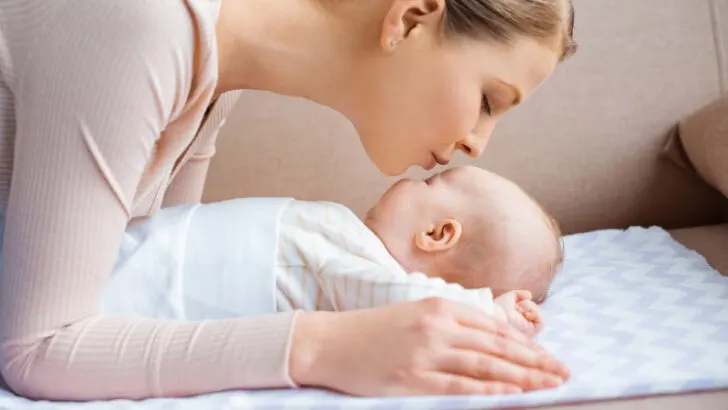 new mom kissing newborn baby's forehead