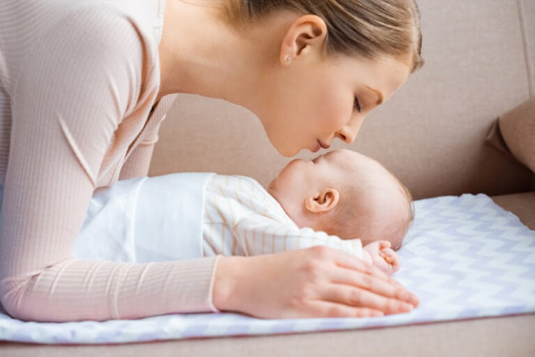 new mom kissing newborn baby's forehead