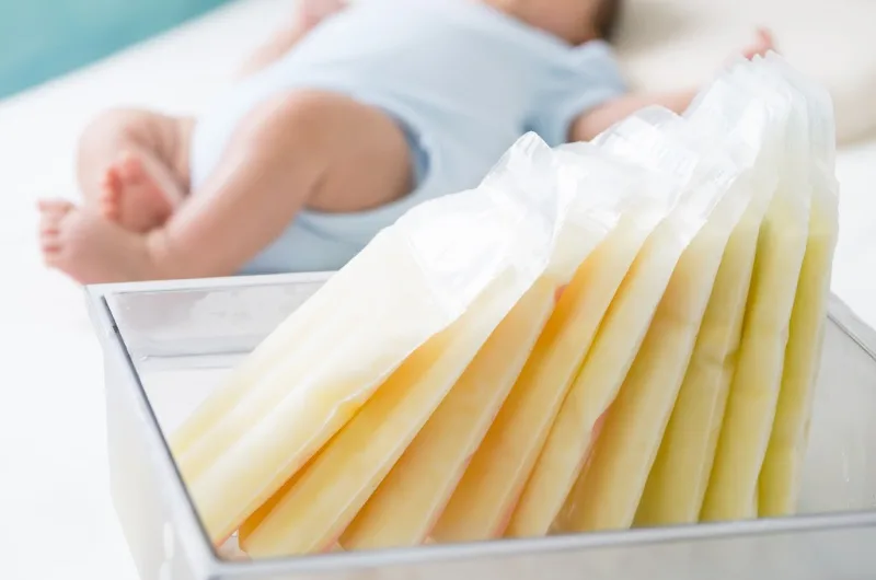plastic bags of frozen breastmilk standing in breast milk storage container