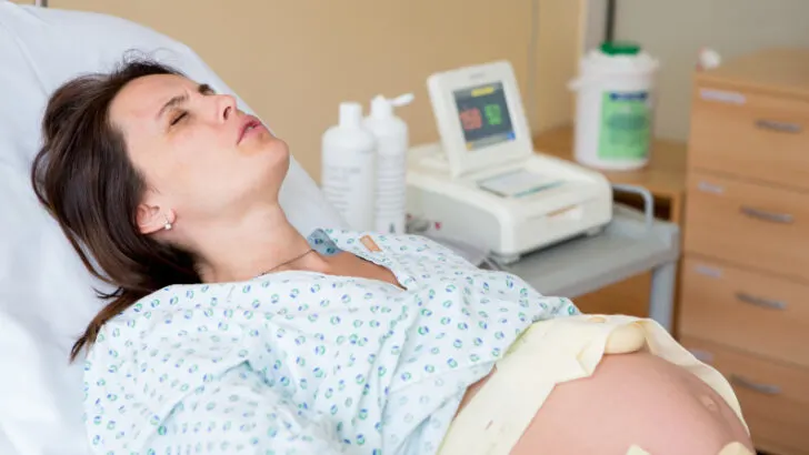 pregnant woman in pain during labor, lying on hospital bed
