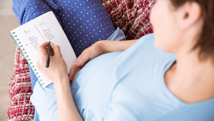 Pregnant Woman Writing Unique Baby Names on a Notepad