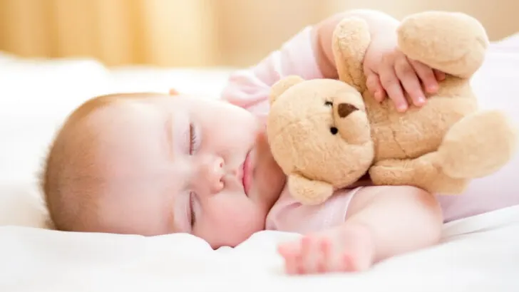 adorable sleeping baby girl holding teddy bear