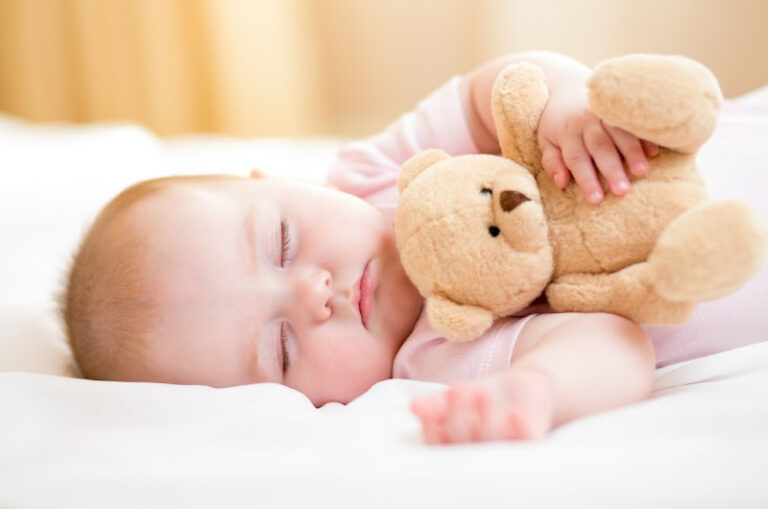 adorable sleeping baby girl holding teddy bear