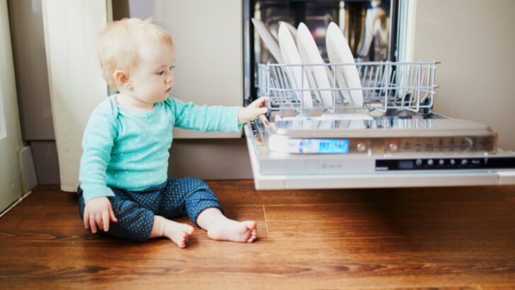 baby touching dishes in dishwasher