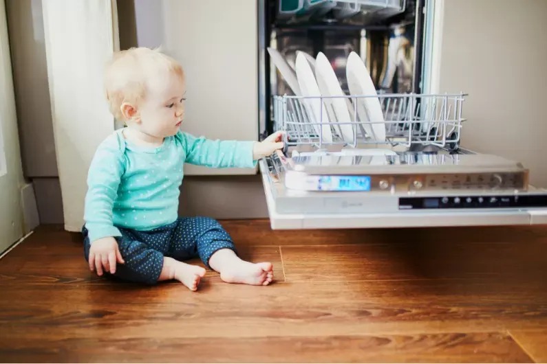 baby touching dishes in dishwasher