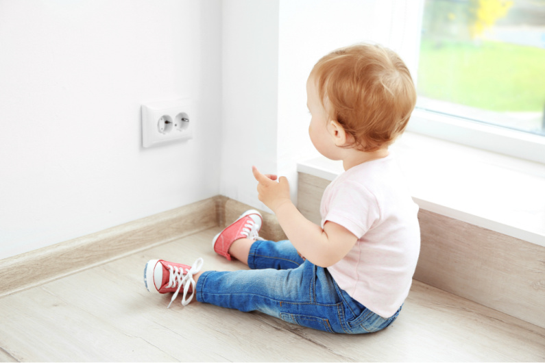 baby looking at electrical outlet, considering touching it