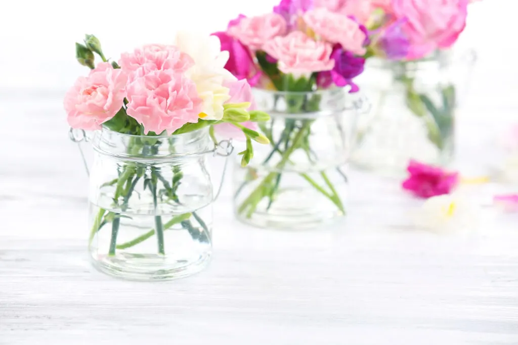 minimalist baby shower table decor, simple flowers in mason jars.
