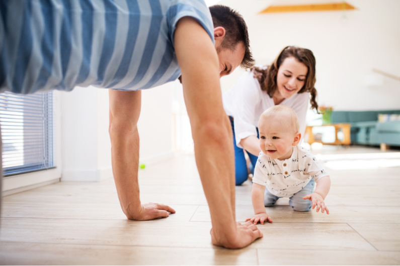 parents crawling on the floor with their baby.