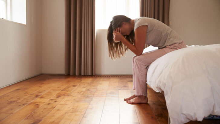 woman, sitting on side of bed, grieving miscarriage