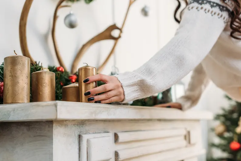 woman setting out candles for Christmas on side table.