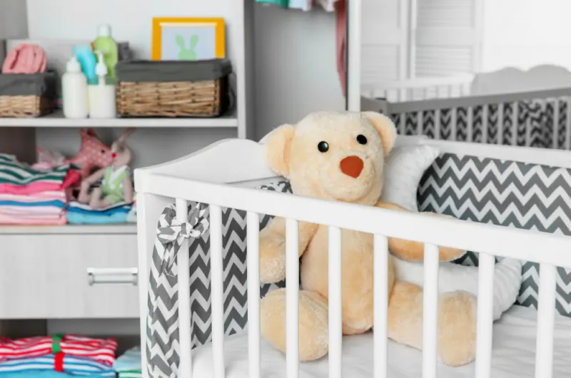stuffed bear in crib in small nursery.