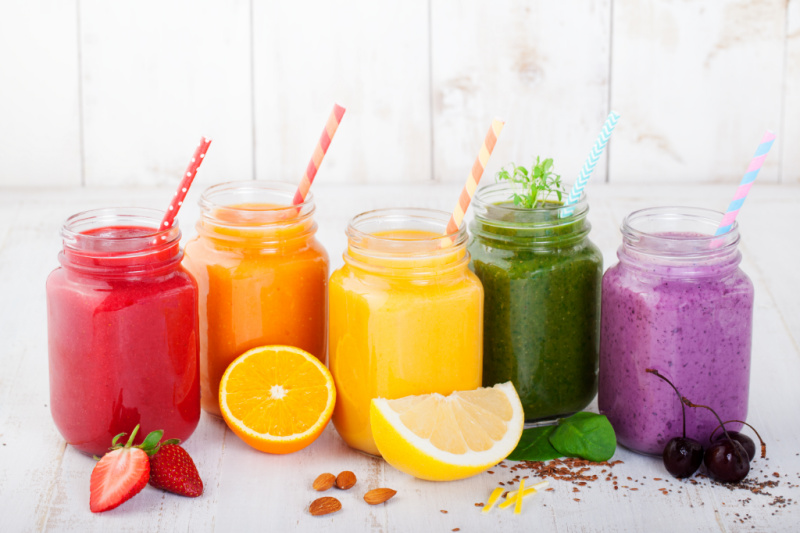 colorful breastfeeding smoothies in mason jars with straws on counter.