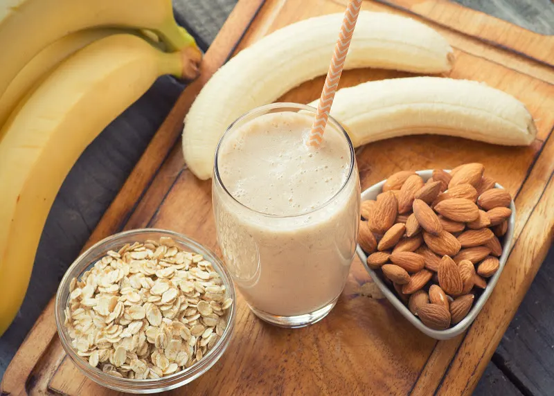 banana lactation smoothie on cutting board with bananas, oats and almonds.