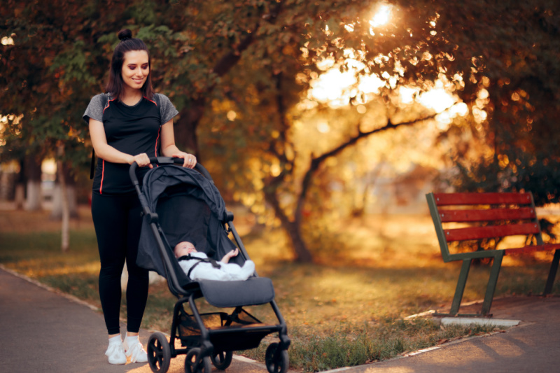 breastfeeding mom walking in workout clothes pushing a stroller trying to lose baby weight while breastfeeding.