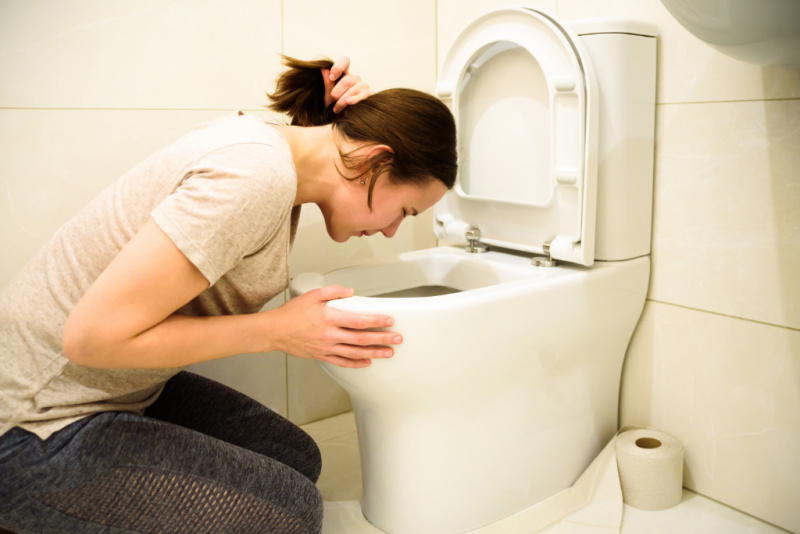 pregnant woman throwing up in toilet because of pregnancy nausea