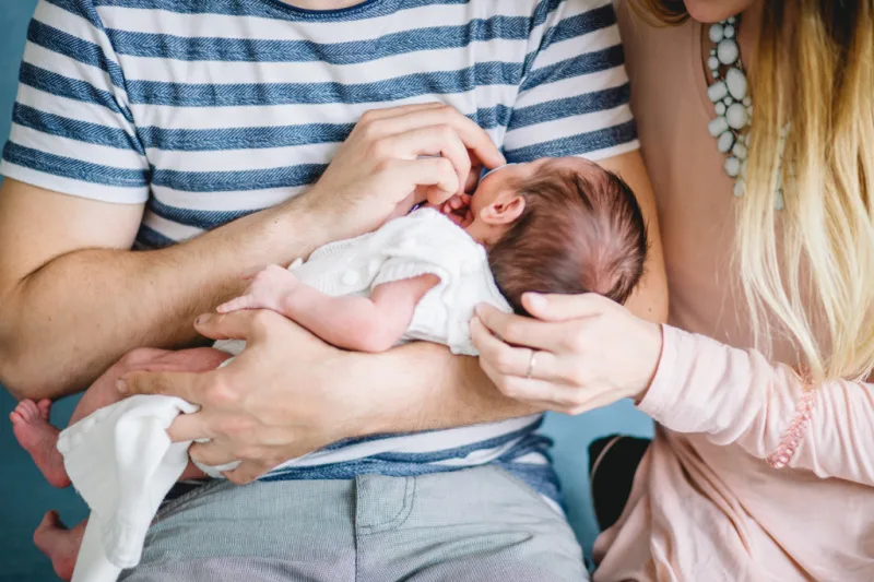 new dad holding newborn, with mom looking on