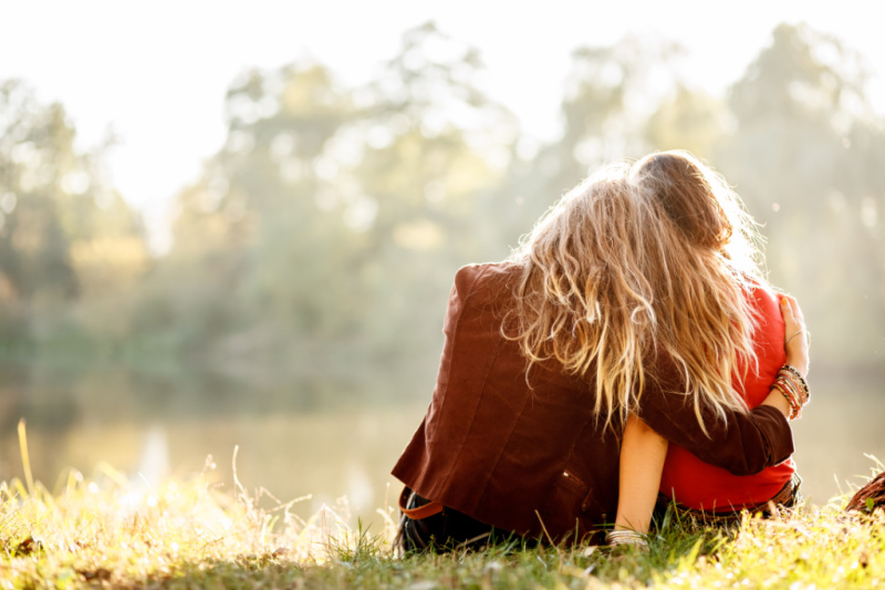 two friends sitting together, one comforting the other who is struggling with infertility.