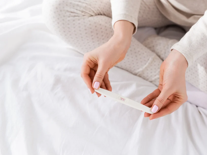 woman's hands holding positive pregnancy test