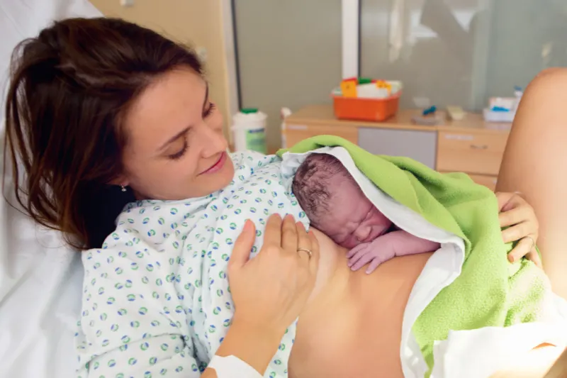 woman who just delivered a baby with newborn on her chest.