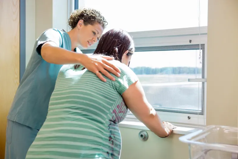 labor and delivery nurse helping mom through natural birth by rubbing back