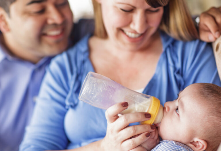 parents holding baby while bottle feeding with formula