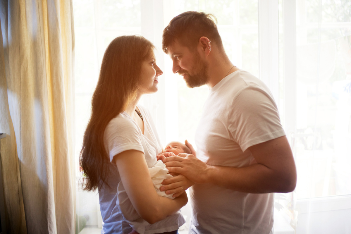 husband and wife, new parents holding their newborn baby