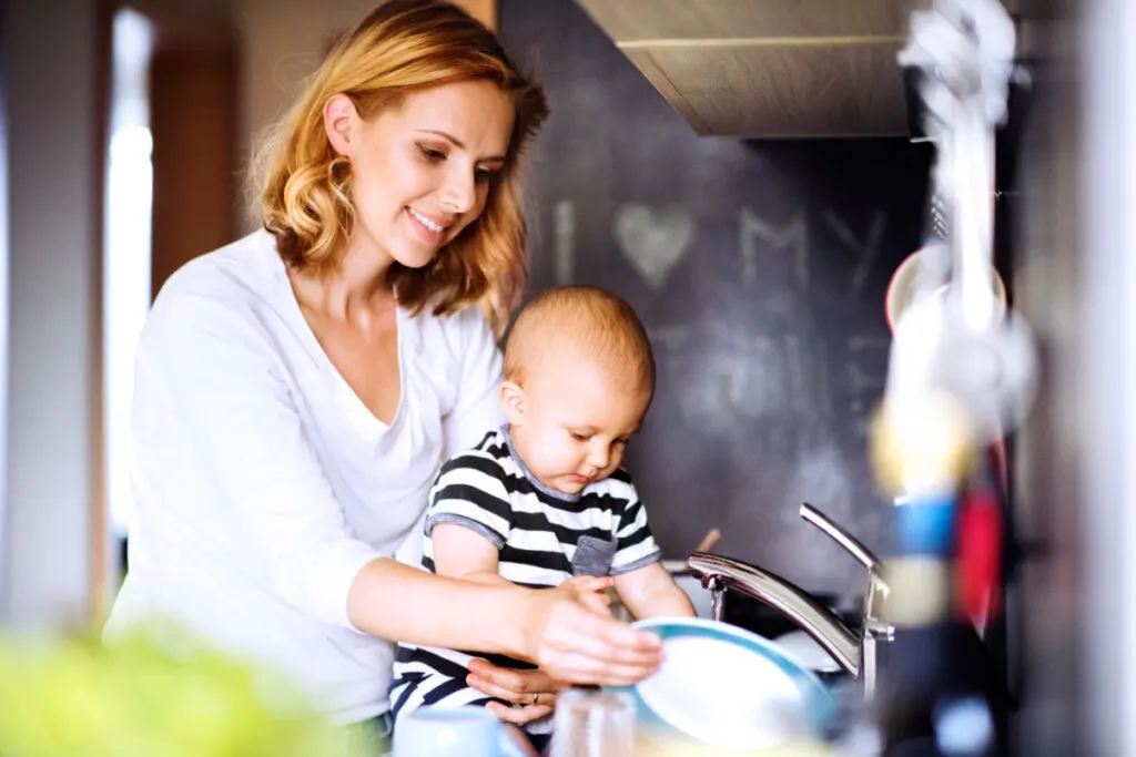 mom doing housework while holding baby