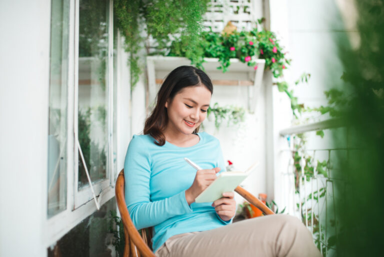 asian new mom writing in journal for self-care
