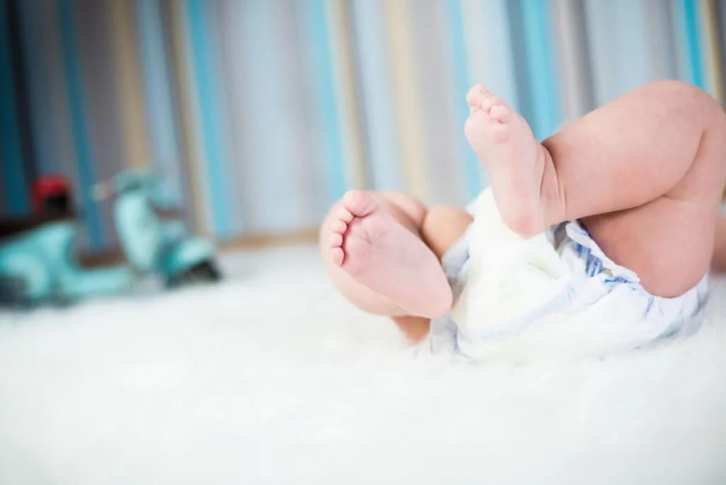 newborn baby lying on nursery carpet wearing only diaper