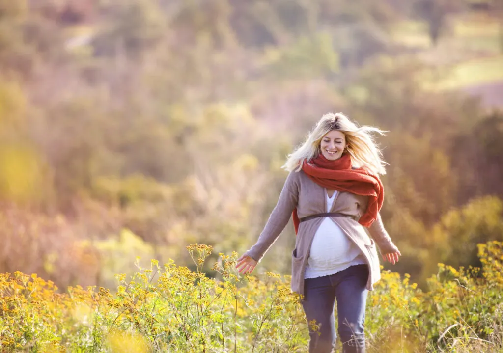 pregnant woman walking in field practicing self care