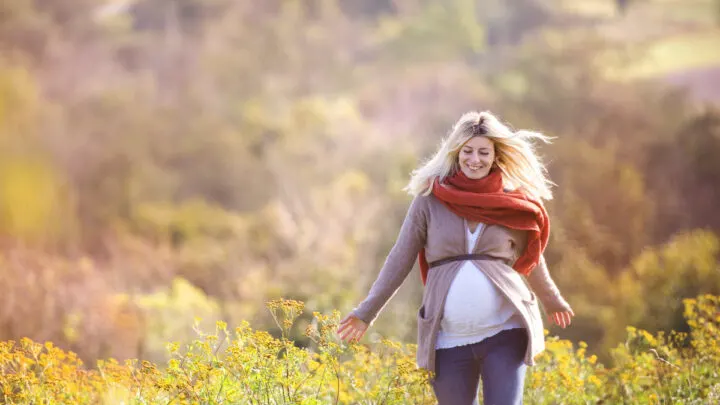pregnant woman walking in field practicing self care