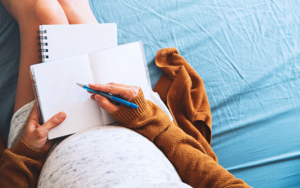 pregnant mom belly, hands and notebooks, taking notes 
