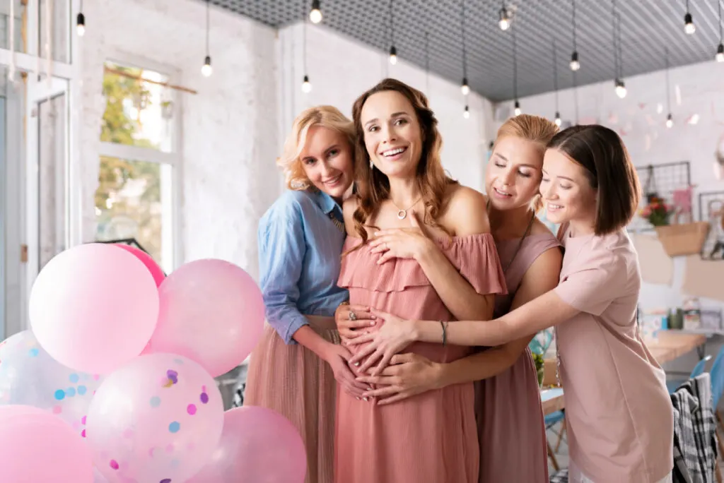 women at baby shower touching mom to be's pregnant belly