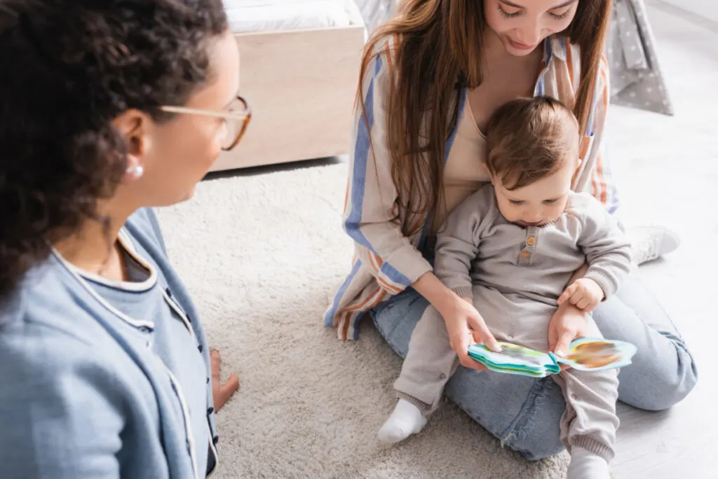 beautiful mom reading Sandra Boynton book to baby on her lap