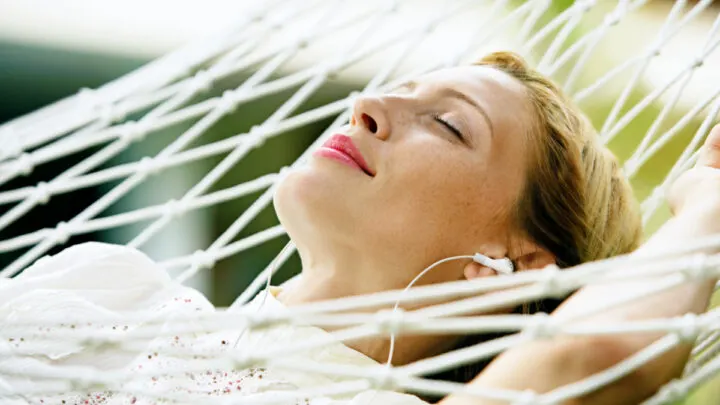 new mom resting in hammock enjoying self-care gift of new headphones