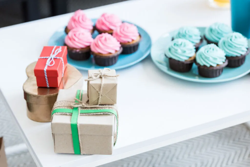 red and blue frosted cupcakes with baby shower gifts