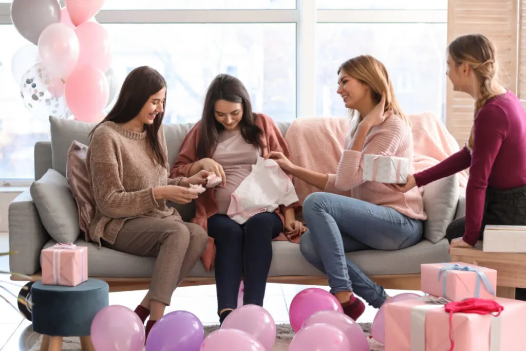 women at baby shower, pregnant woman opening gifts