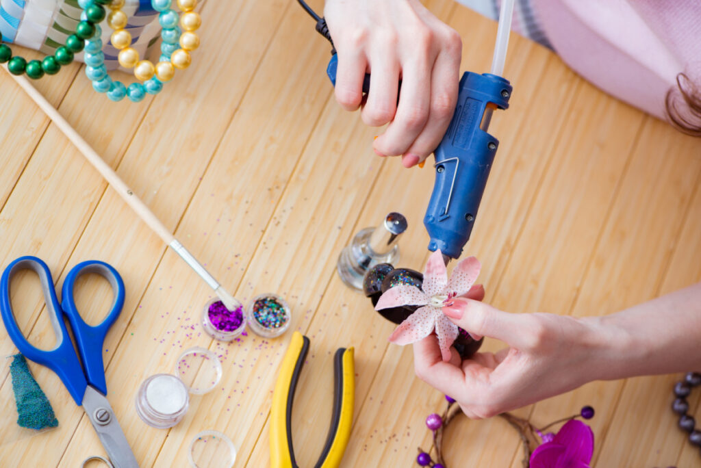 woman making jewelry on table with glue gun