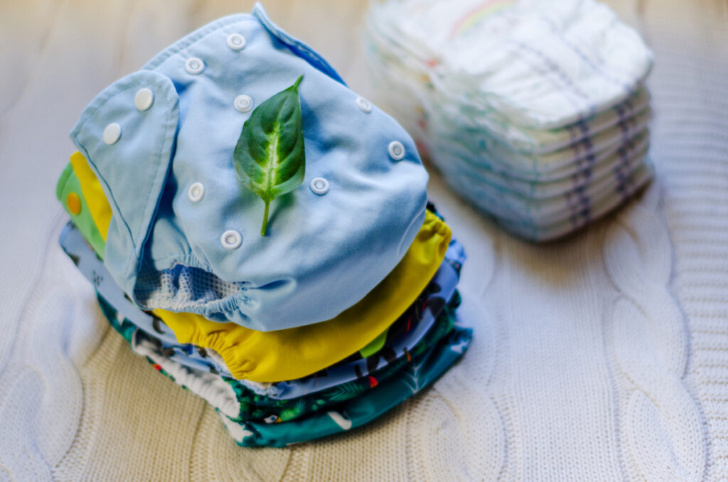 a stack of colorful cloth diapers next to a stack of disposables