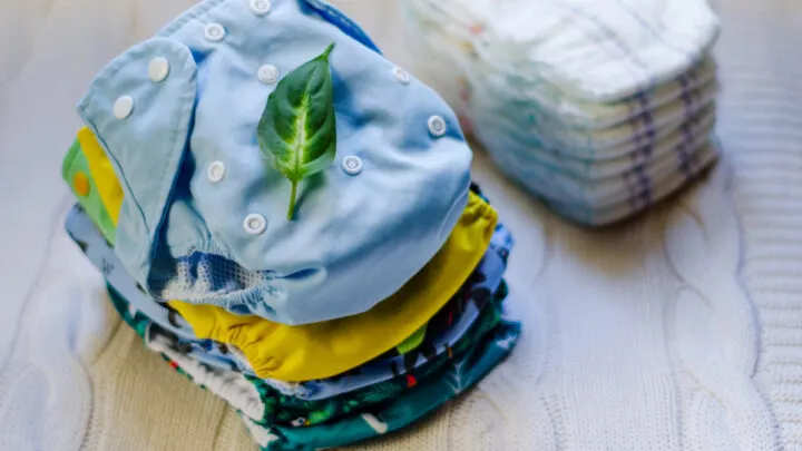a stack of colorful cloth diapers next to a stack of disposables