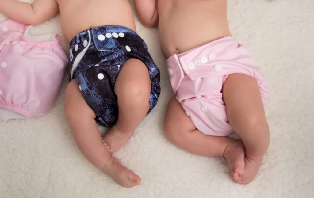 cloth diapered babies lying side by side, photography from chest down