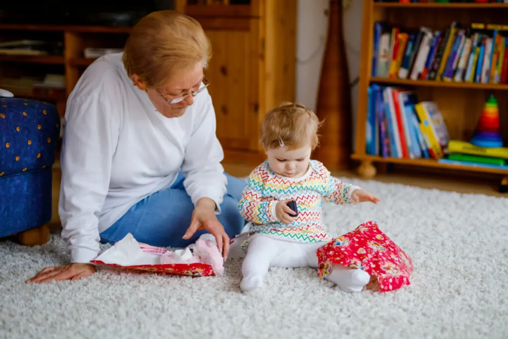 grandmother brought baby a gift, baby plays with unwrapped gift