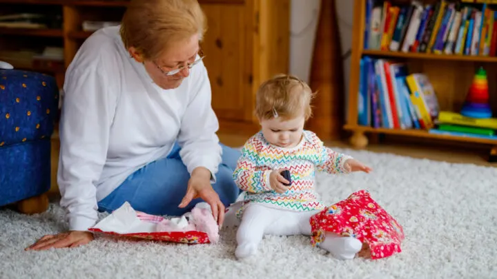 grandmother brought baby a gift, baby plays with unwrapped gift