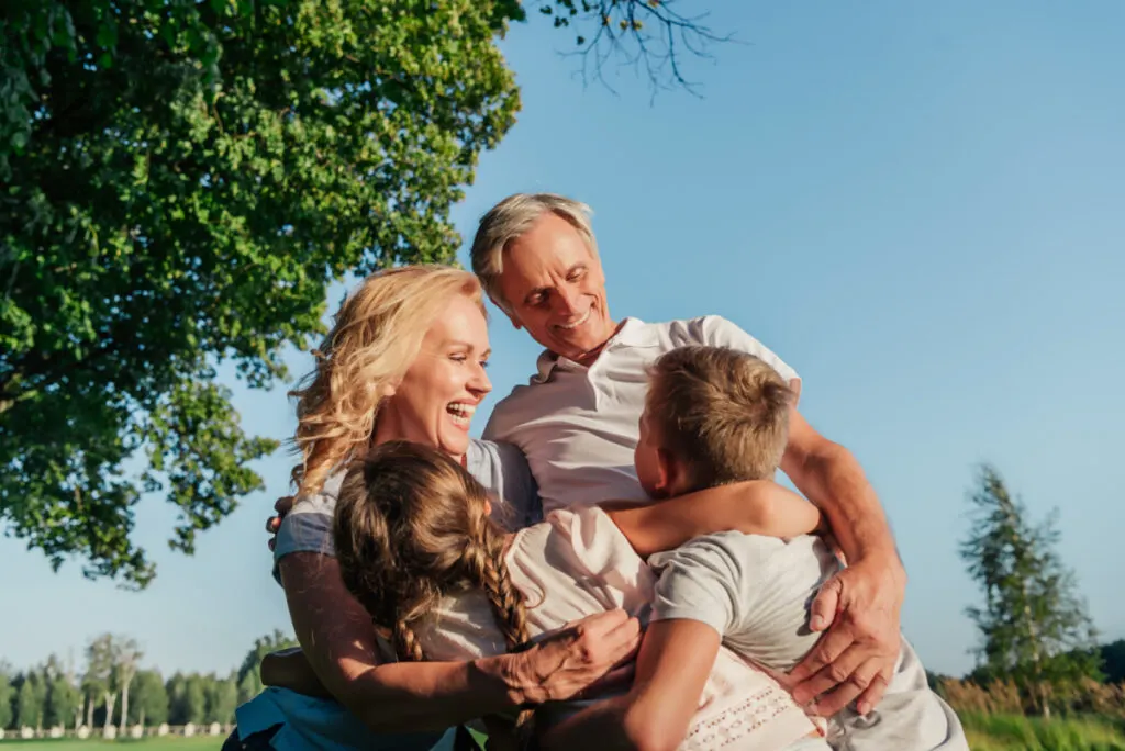 happy grandparents hugging their grandkids outside