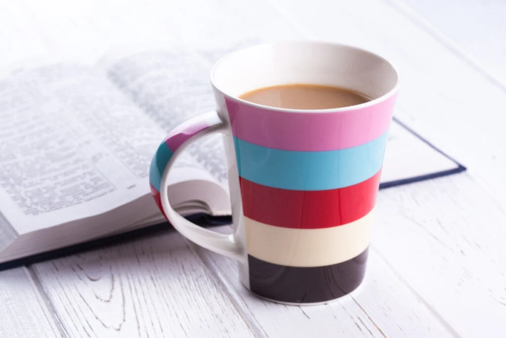 colorful striped coffee mug on table with Bible verses