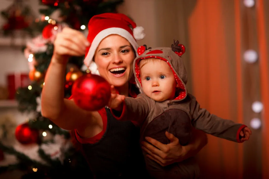 mom hanging Christmas ornaments with a baby