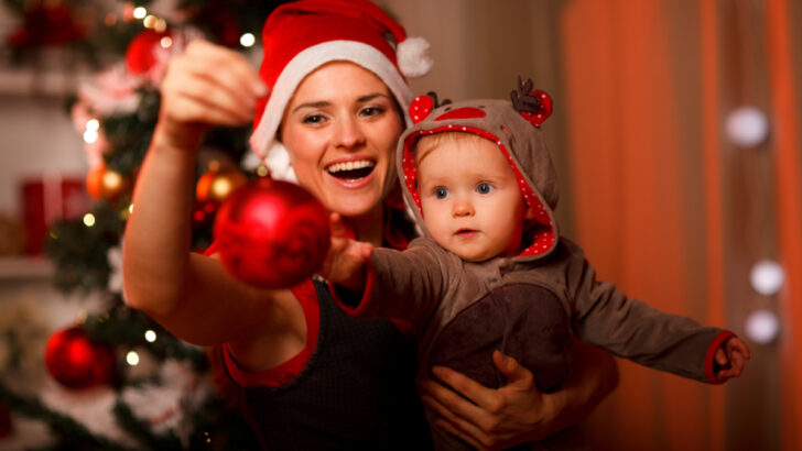 mom hanging Christmas ornaments with a baby