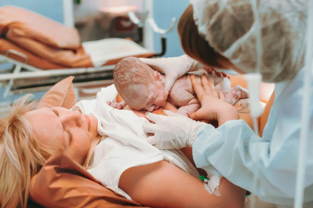 woman right after birth with newborn on chest struggling with urinary retention