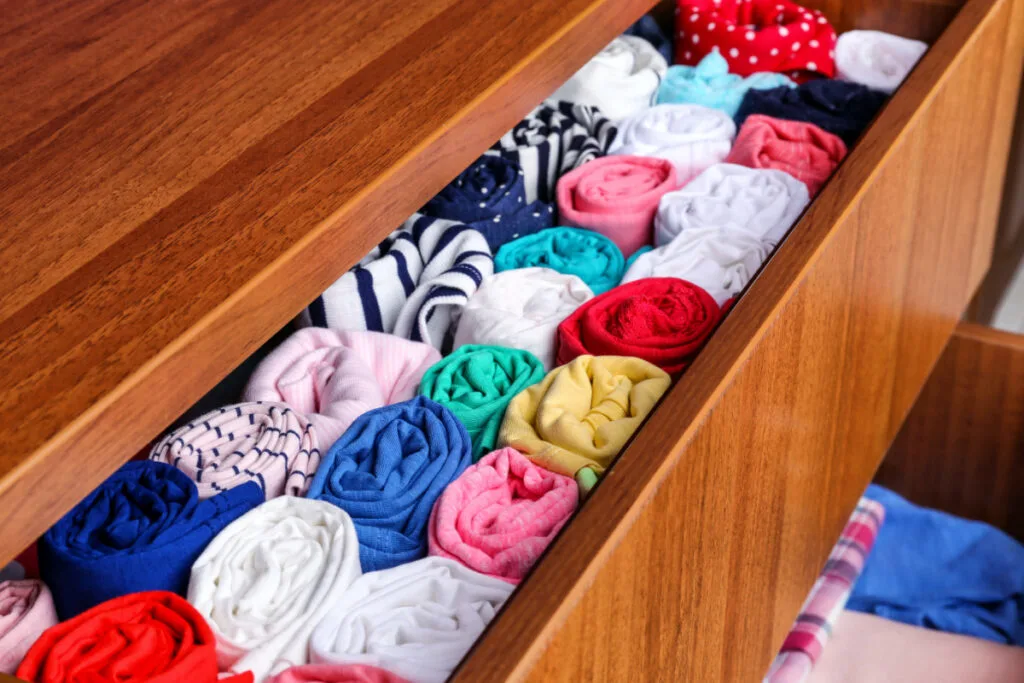 drawer with colorful baby clothes rolled and standing upright in drawer