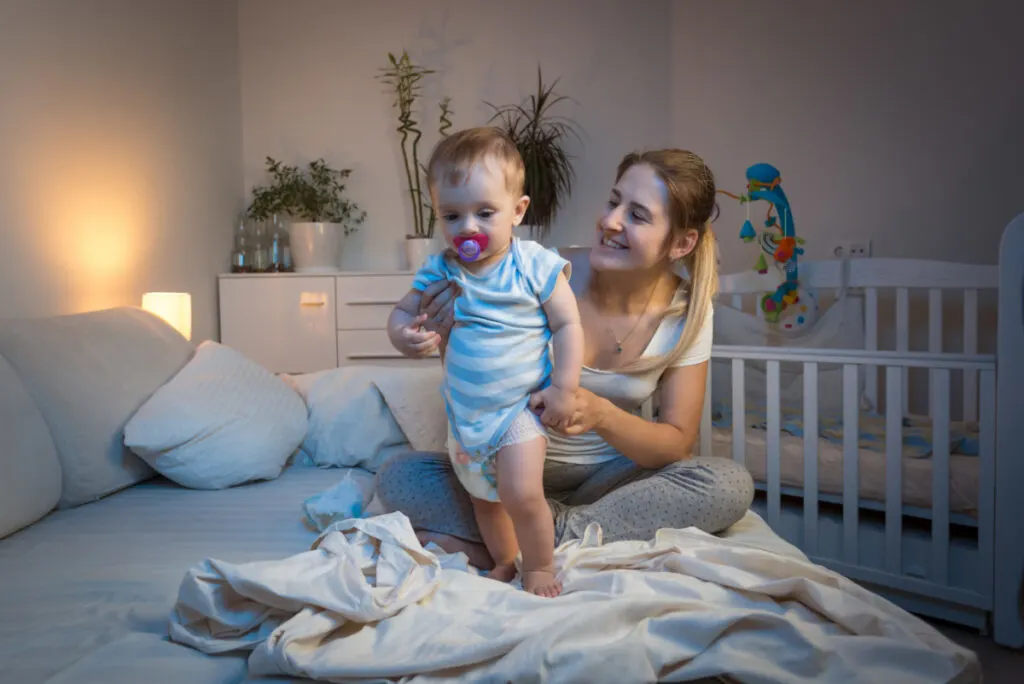 Mother changing a diaper in the middle of the night because baby peed through the diaper